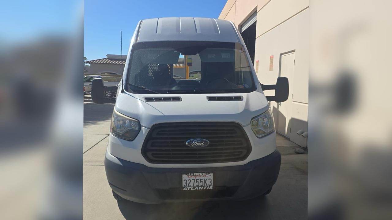 Front view of a white Ford van parked in a driveway with a clear blue sky above.